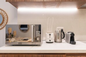 A kitchen counter with a microwave, toaster, kettle, and coffee maker. - bnbme - La Cote 3 - 1BR (Dubai)