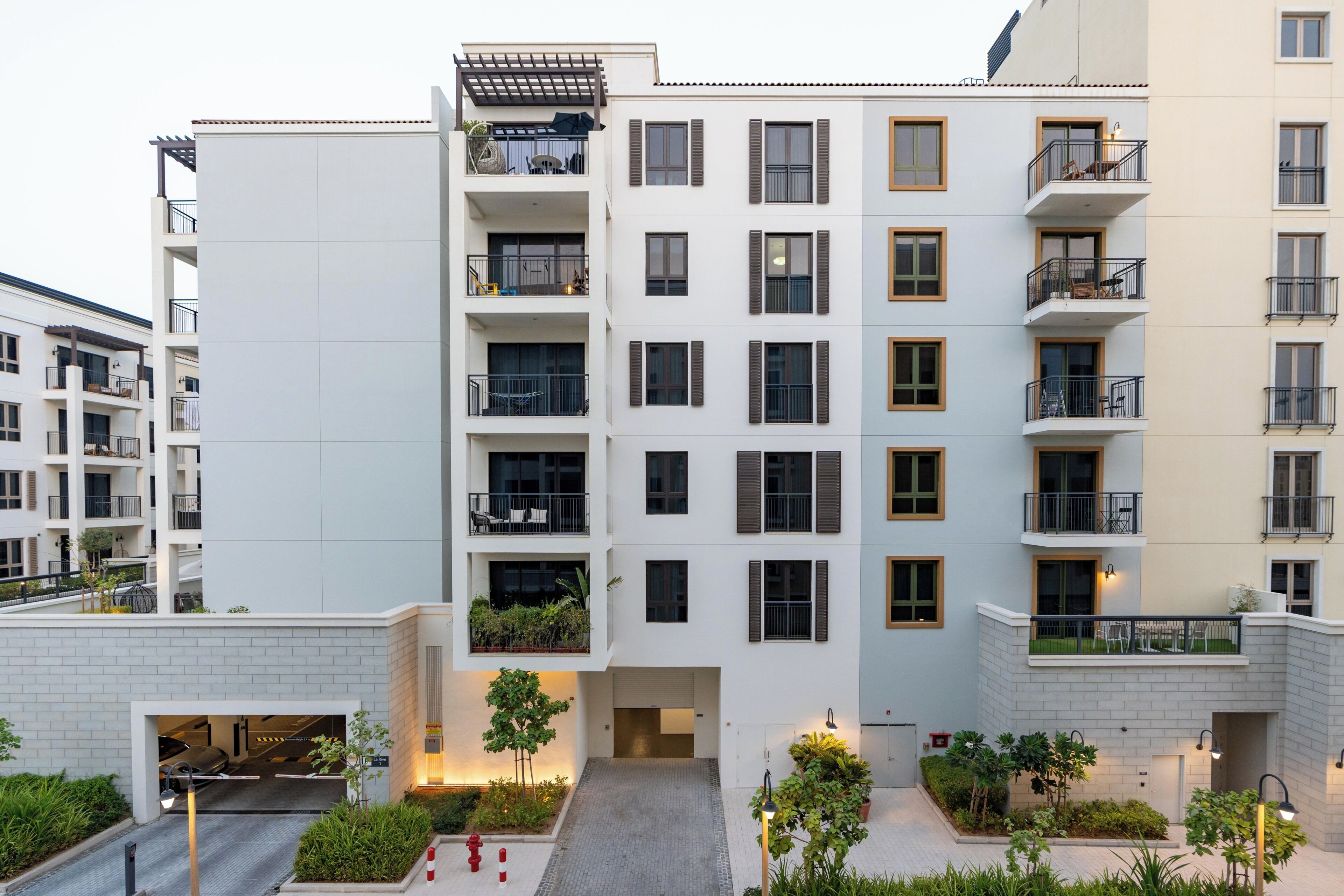 A multi-story residential building with balconies, a gated entrance, and a landscaped courtyard.