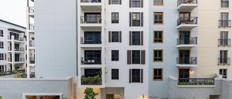 A multi-story residential building with balconies, a gated entrance, and a landscaped courtyard.