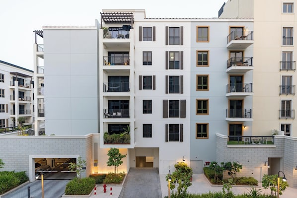 A multi-story residential building with balconies, a gated entrance, and a landscaped courtyard. - bnbme - La Cote 3 - 1BR (Dubai)