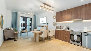 A modern kitchen with wooden cabinets, stainless steel appliances, and a dining area with a table and chairs.