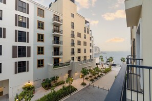 Um hotel de vários andares com varandas, vista para a orla marítima e um pátio ajardinado.