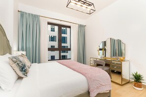 A bedroom with a bed, a dresser, a mirror, and a window with curtains. - bnbme - La Cote 3 - 1BR (Dubai)