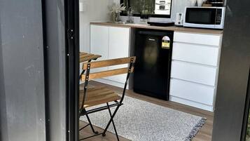 A compact kitchen with white cabinets, a black refrigerator, and a microwave.