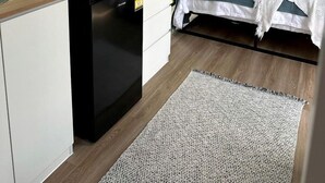 A compact bedroom with a bed, bedside table, and a window.