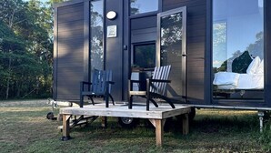 A modern, compact cabin with a deck, seating area, and a visible bed inside.
