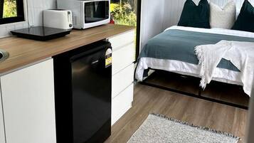 A compact bedroom with a bed, bedside table, and a window.