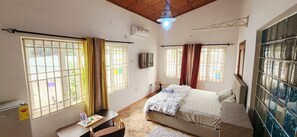 A bedroom with a bed, a desk, and a window with curtains. - Premium Single Room Ne A&C Mall W/ Premium Amenity (Accra)
