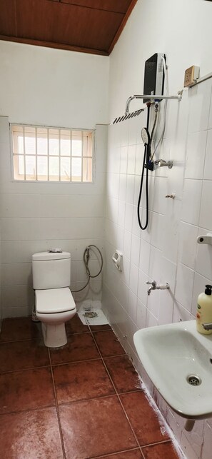 A small, basic bathroom with a toilet, a sink, and a shower. - Premium Single Room Ne A&C Mall W/ Premium Amenity (Accra)