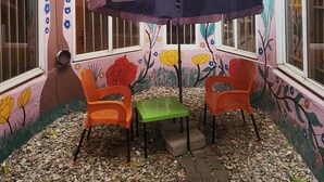 Een kamer met dakraam, een tafel met stoelen, en wanden versierd met bloemen- en boommuurschilderingen.