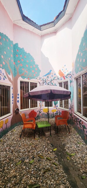 A room with a skylight, a table with chairs, and walls decorated with floral and tree murals. - Premium Single Room Ne A&C Mall W/ Premium Amenity (Accra)