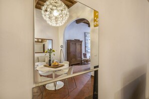 A dining area with a round table, white chairs, a vase with flowers, and a chandelier. - Via Maggio 10 – Historic 1 Bedroom in Oltrarno (Florence)