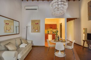 A living room with a sofa, a dining table with chairs, and artwork on the walls. - Via Maggio 10 – Historic 1 Bedroom in Oltrarno (Florence)