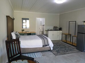 A compact room with a bed, a small kitchenette, a mirror, and a refrigerator. - Cape Mesa Starting Point (Cape Town)