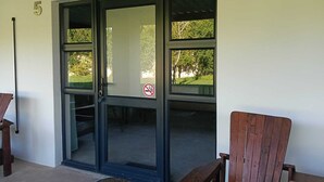 Ein Gebäudeeingang mit Glastür, der Hausnummer 5 an der Wand und einem Rauchverbot-Schild.