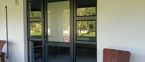 A building entrance with a glass door, a number '5' on the wall, and a no-smoking sign.