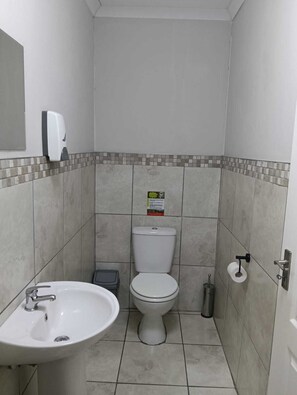 A small, clean bathroom with a white sink, toilet, and hand dryer. - Cape Mesa Starting Point (Cape Town)