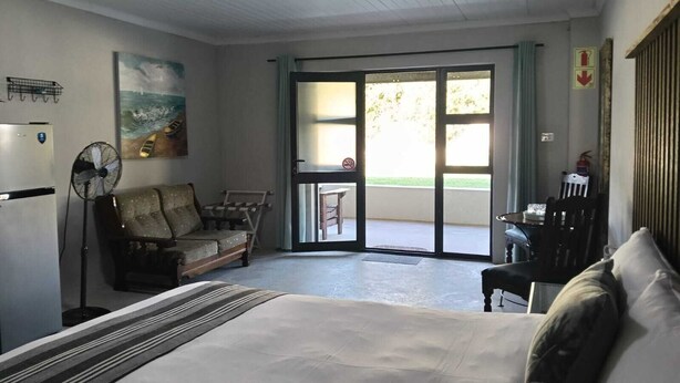 Ein Zimmer mit einem Bett, einem Ventilator, einem Tisch und einem Stuhl.