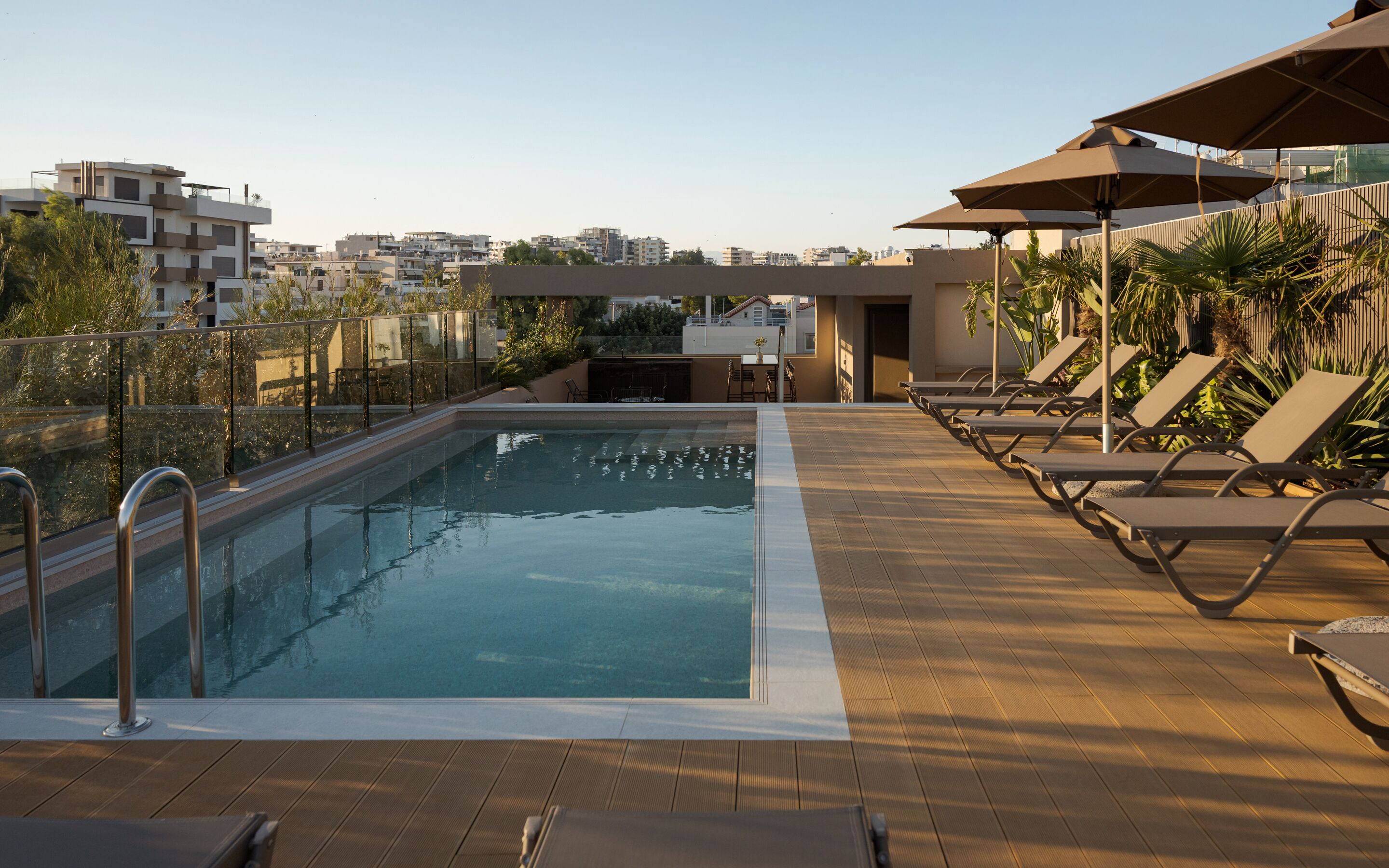 Piscina en la azotea con tumbonas y vistas a la ciudad.
