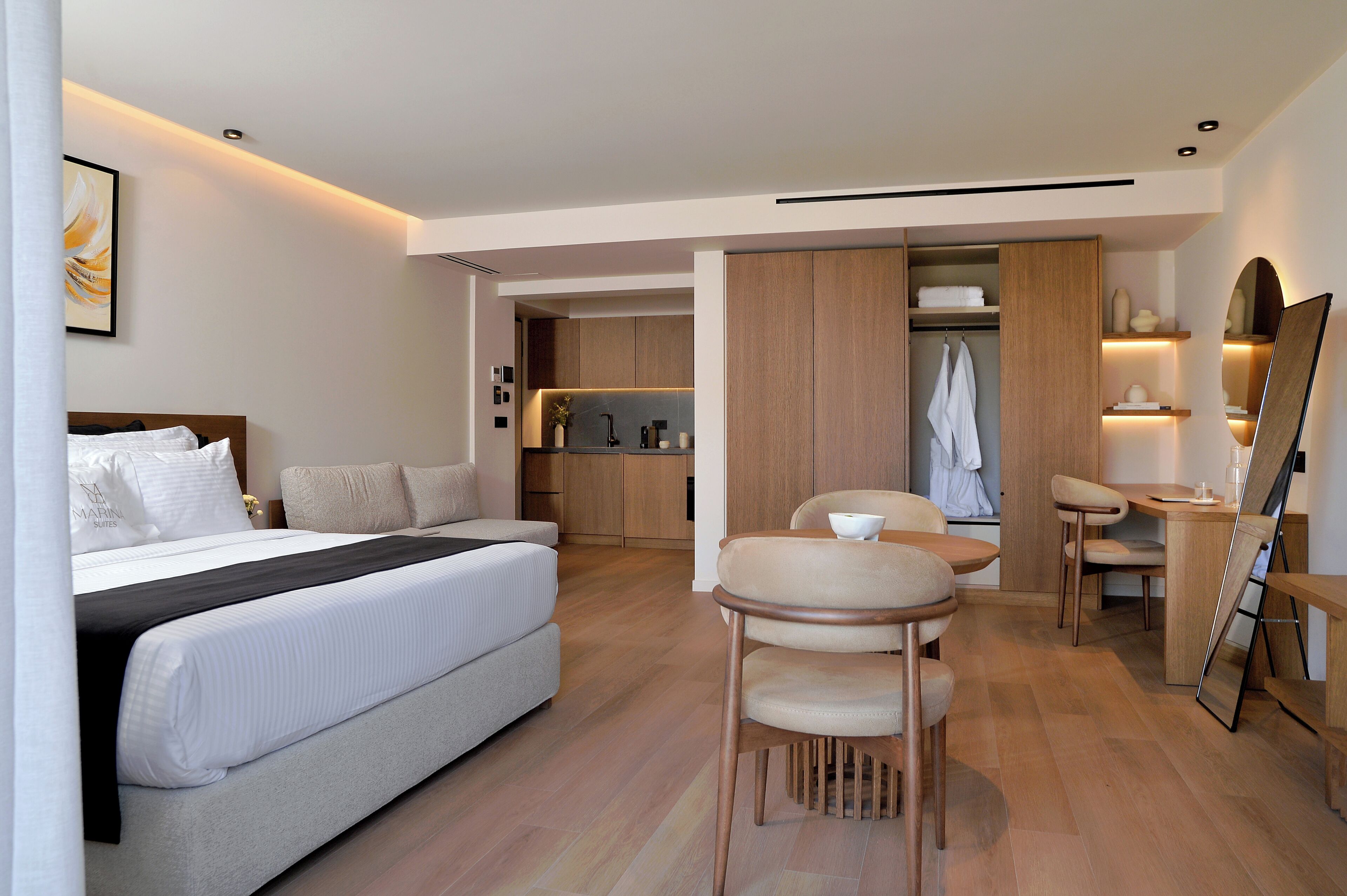 A modern hotel room with a bed, a dining area, and a bathroom.