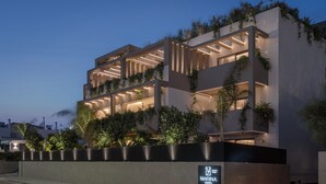 A multi-story hotel with balconies, a sign indicating 'MARINA SUITES,' and a gated entrance.