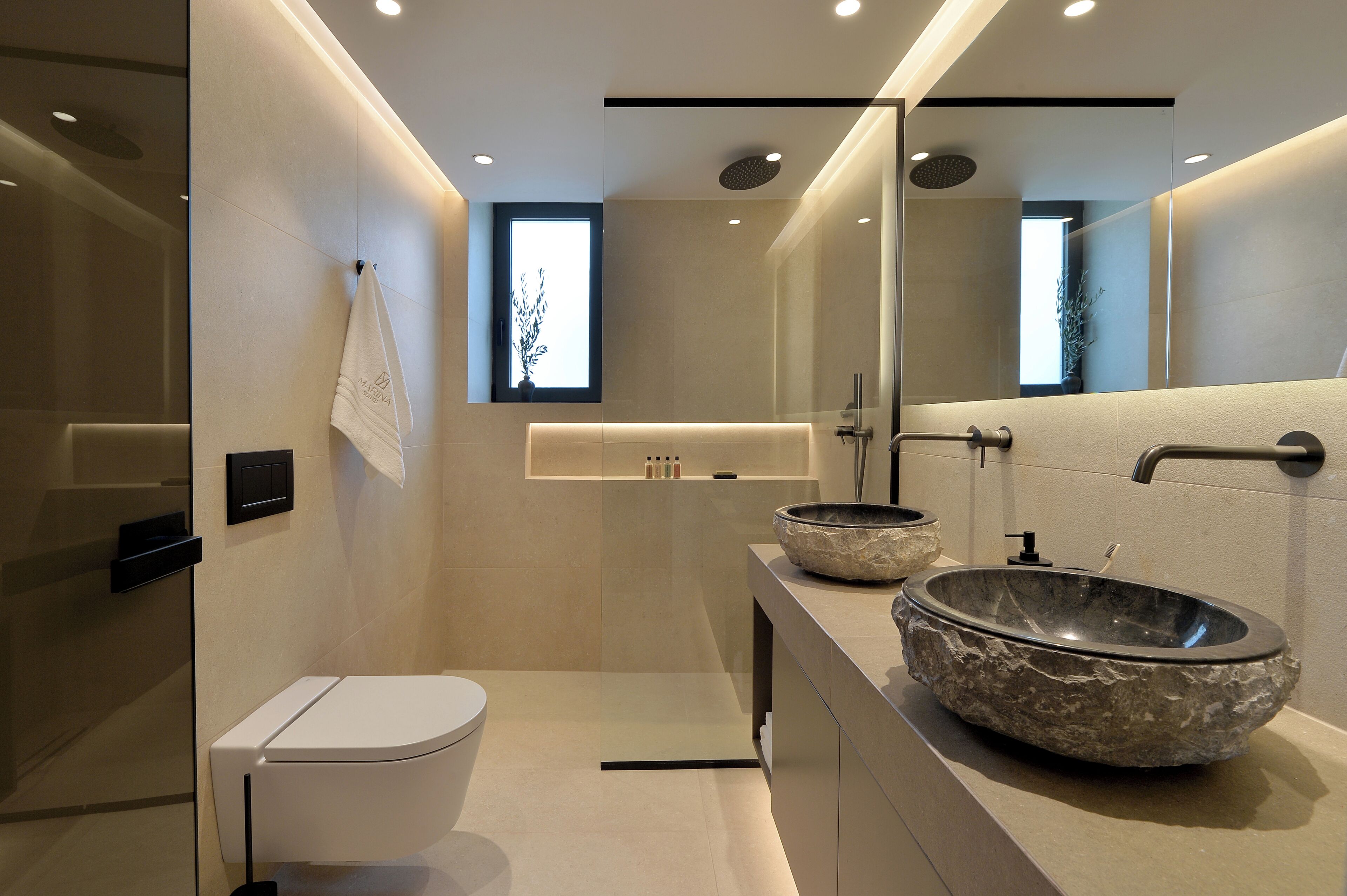 A modern bathroom with a toilet, a large basin sink, and a mirror.