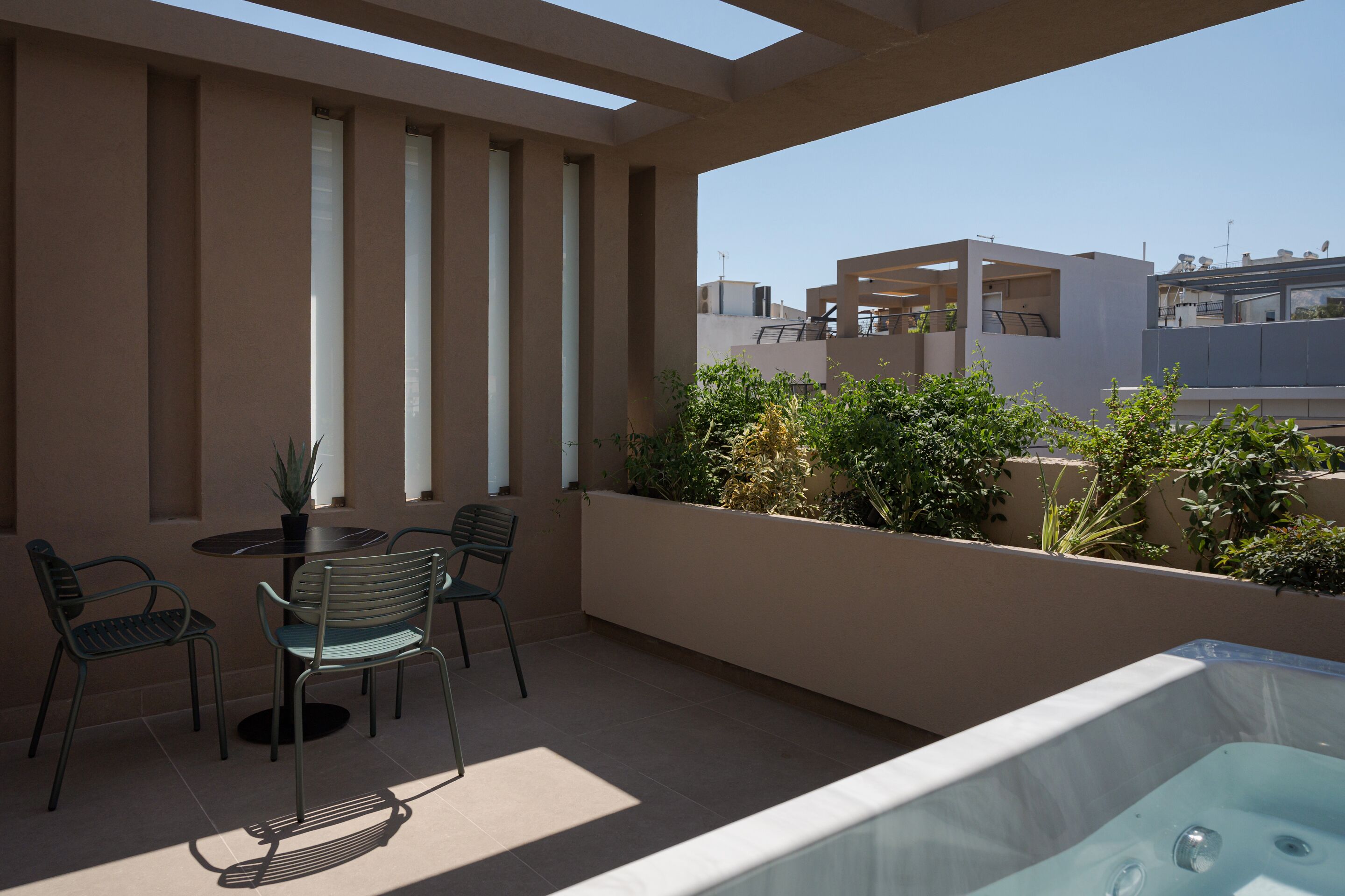 A rooftop terrace with a hot tub, seating area, and potted plants.