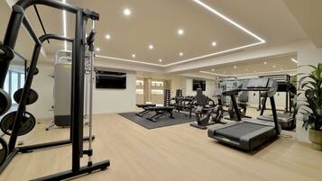 A modern gym with various exercise equipment, a flat-screen TV, and a large mirror.