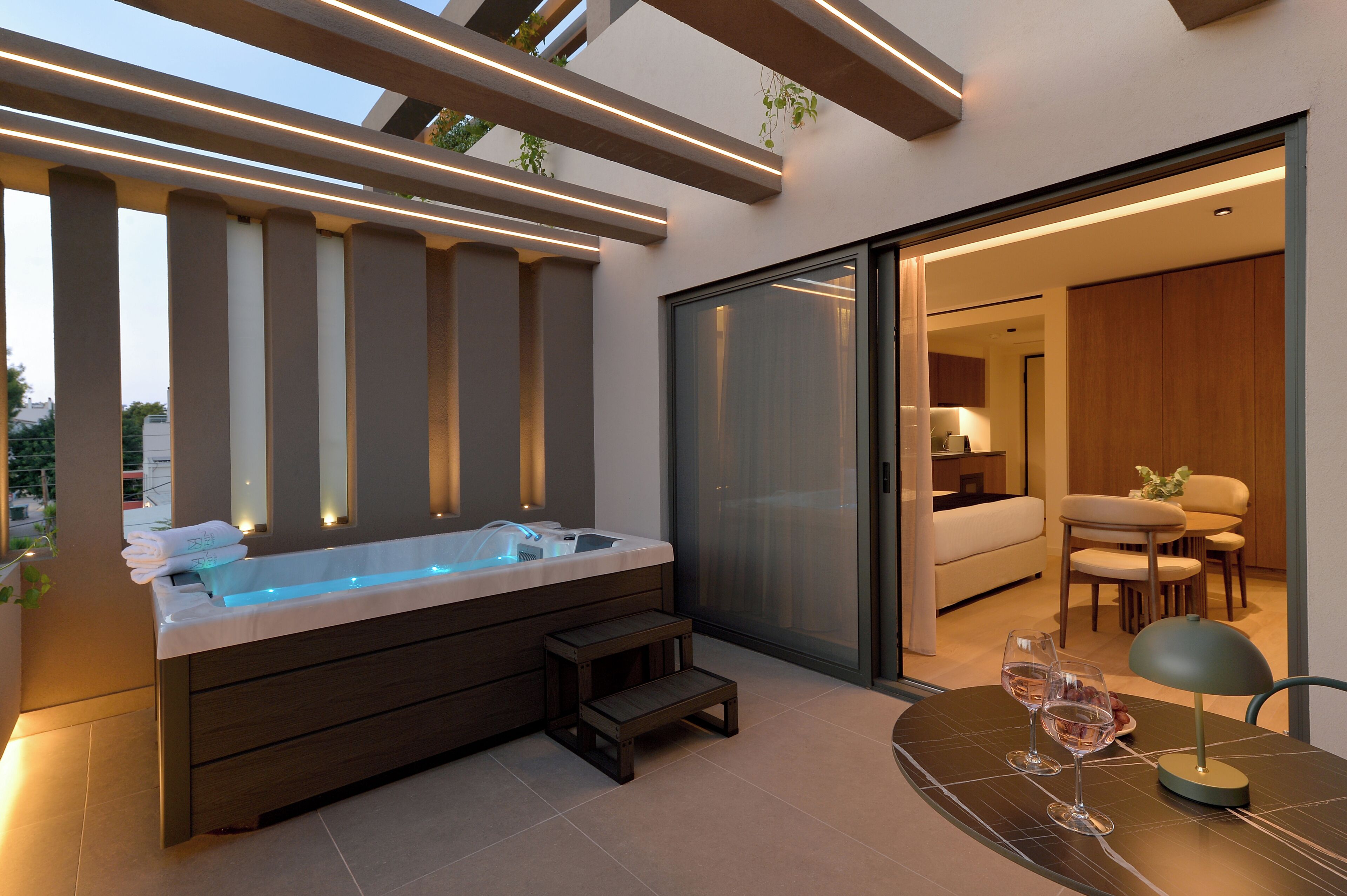 A modern outdoor hot tub area with a glass door leading to a dining space.