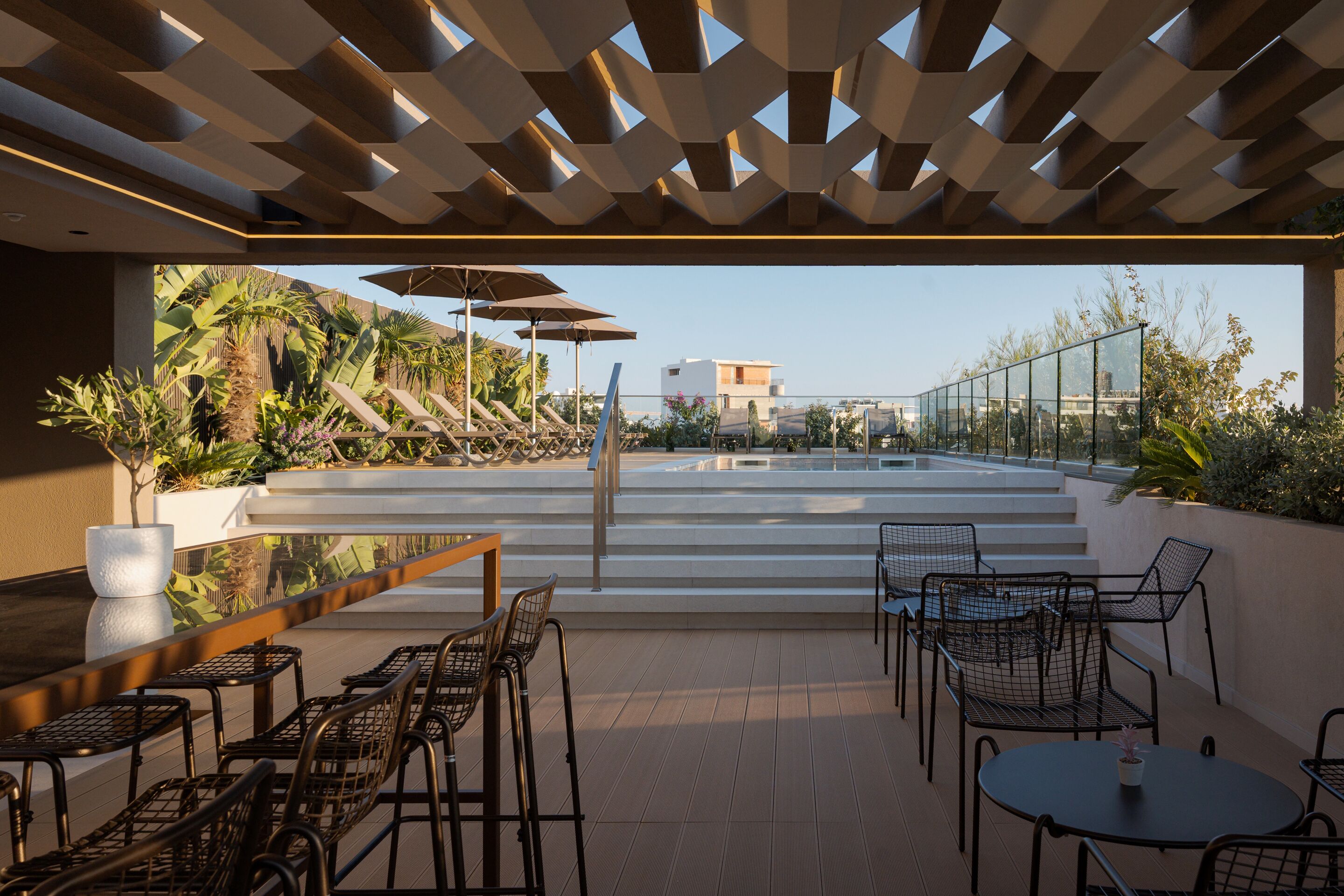 Terraço no telhado com piscina, área de estar ao ar livre e vista para o horizonte da cidade.