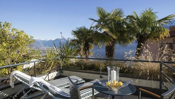 A terrace with a table and chairs, overlooking a mountainous landscape.