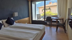 A hotel room with two beds, a small table, and a chair.