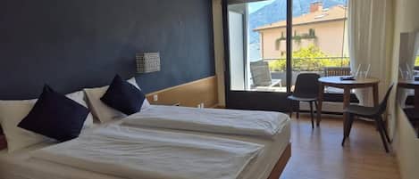 A hotel room with two beds, a small table, and a chair.