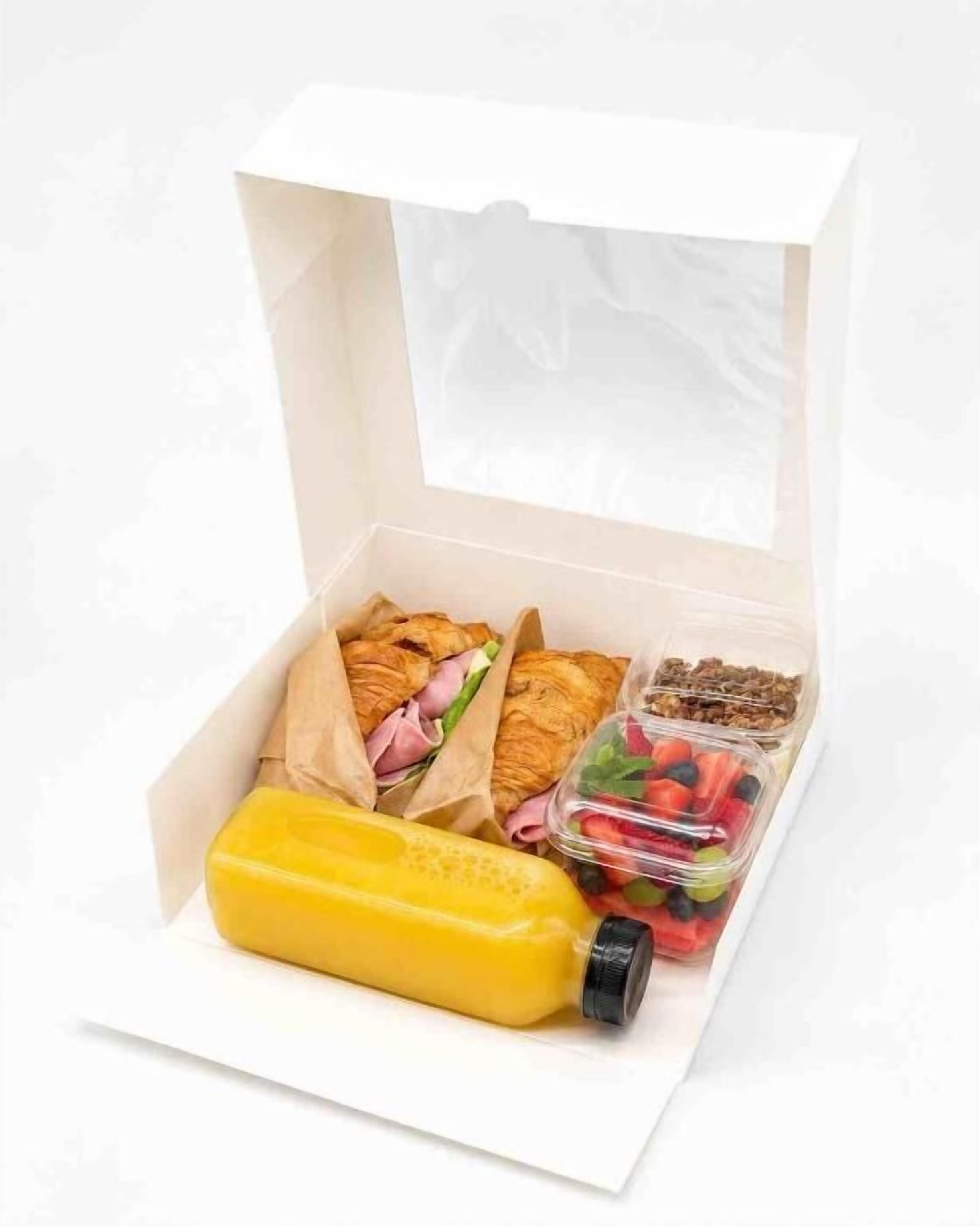 Una lonchera con sándwiches, una botella de jugo y un recipiente con frutos rojos.