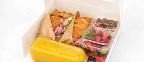 Eine Lunchbox mit Sandwiches, einer Saftflasche und einer Schale mit Beeren.