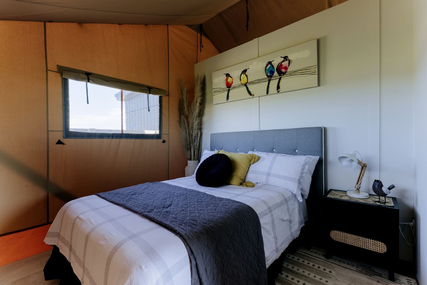 A bedroom with a bed, a nightstand, a lamp, and a wall art piece.