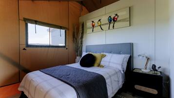 A bedroom with a bed, a nightstand, a lamp, and a wall art piece.