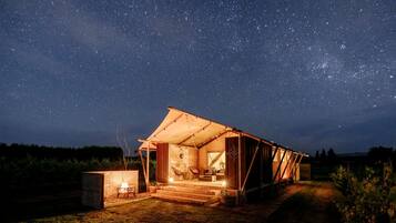 A tent-like structure with a starry night sky visible through the open sides, a small fire pit, and a pathway leading to the entrance.