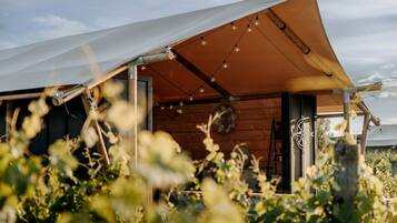A rustic wooden cabin with a large awning, a compass, and string lights.