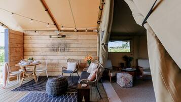 A cozy interior with a wooden wall, a round table with chairs, a sofa, and a small side table with a vase of flowers.