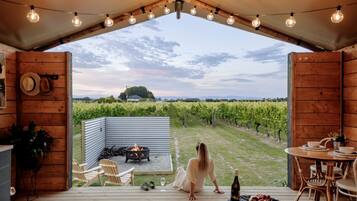A wooden deck with a fire pit, outdoor seating, and a view of a vineyard.