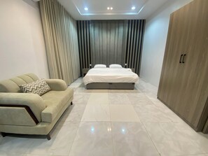 A modern bedroom with a bed, a sofa, and a wardrobe.