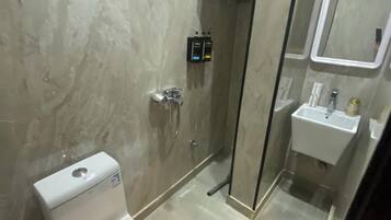 A modern bathroom with a toilet, a shower enclosure, and a sink.