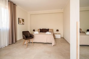Een hotelkamer met een bed, een stoel, een nachtkastje en een kunstwerk aan de muur.