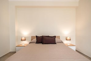 A bedroom with a bed, two bedside lamps, and a headboard. - Family House Turiddu (Fiumefreddo Sicilia)
