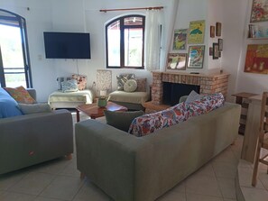 Ein Wohnzimmer mit einer Couch, einem Couchtisch, einem Fernseher, einem Kamin und einem Fenster.
