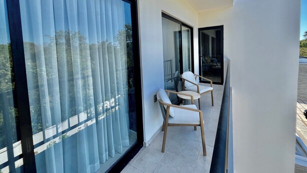 Ein Balkon mit Glastür, einem Stuhl und Blick ins Freie.