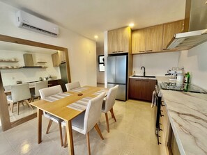 Una cucina moderna con frigorifero integrato, un'area pranzo con tavolo e sedie in legno e un'isola con lavello e fornello.
