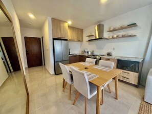 Eine moderne Küche mit Essbereich, ausgestattet mit einem Edelstahlkühlschrank, Holzschränken und einer Mikrowelle.