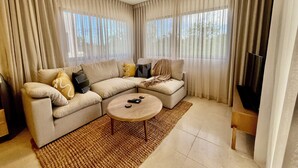 Ein Wohnzimmer mit Ecksofa, Couchtisch und Flachbildfernseher.